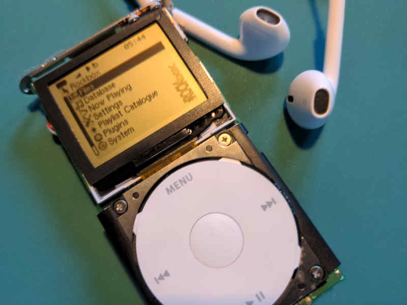 A sylistic image of a disassembled Ipod Mini 2nd Gen that is powered on.